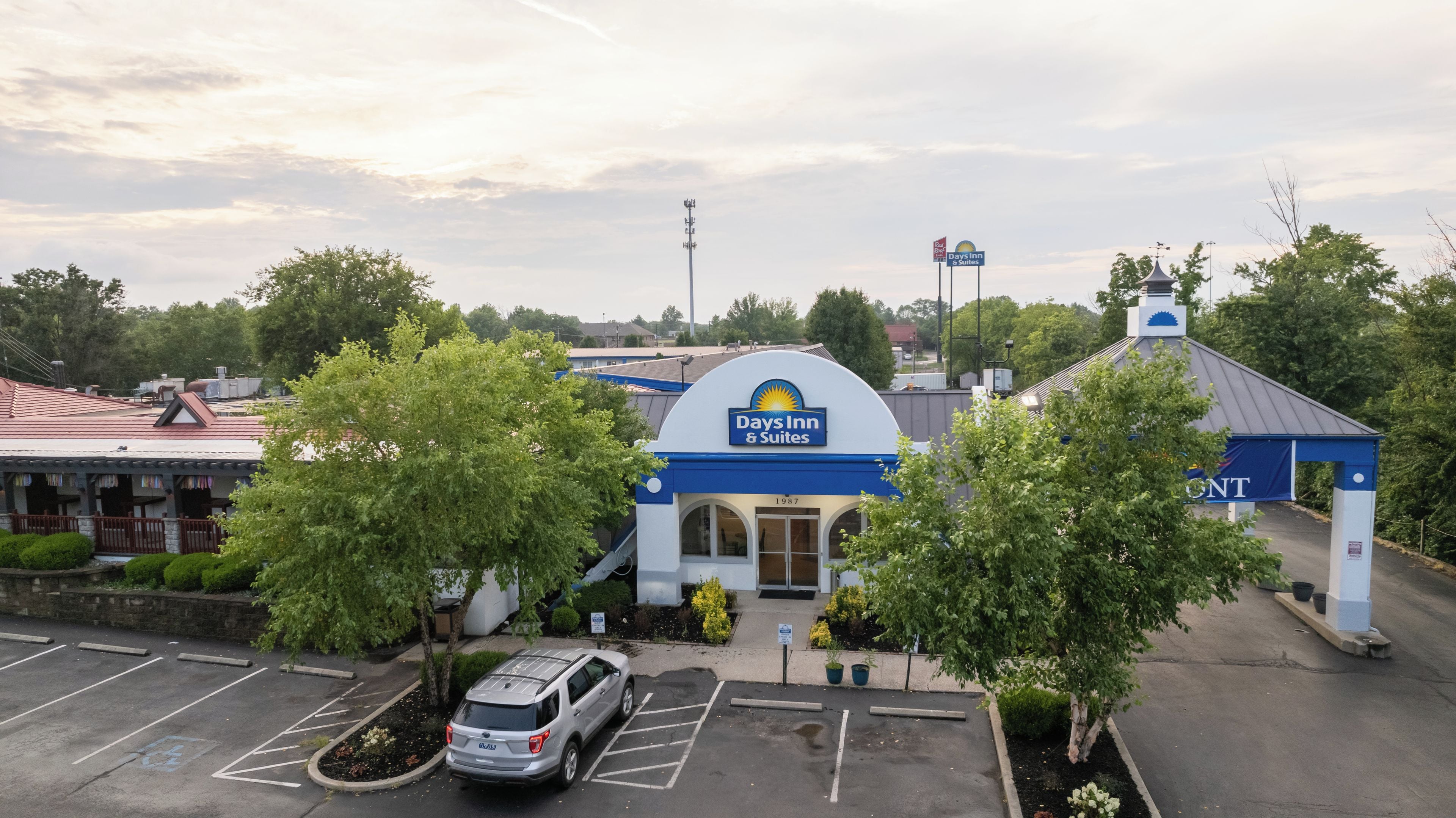 A Days Inn & Suites with a parking lot, a covered outdoor area, and a building with a blue and white color scheme.