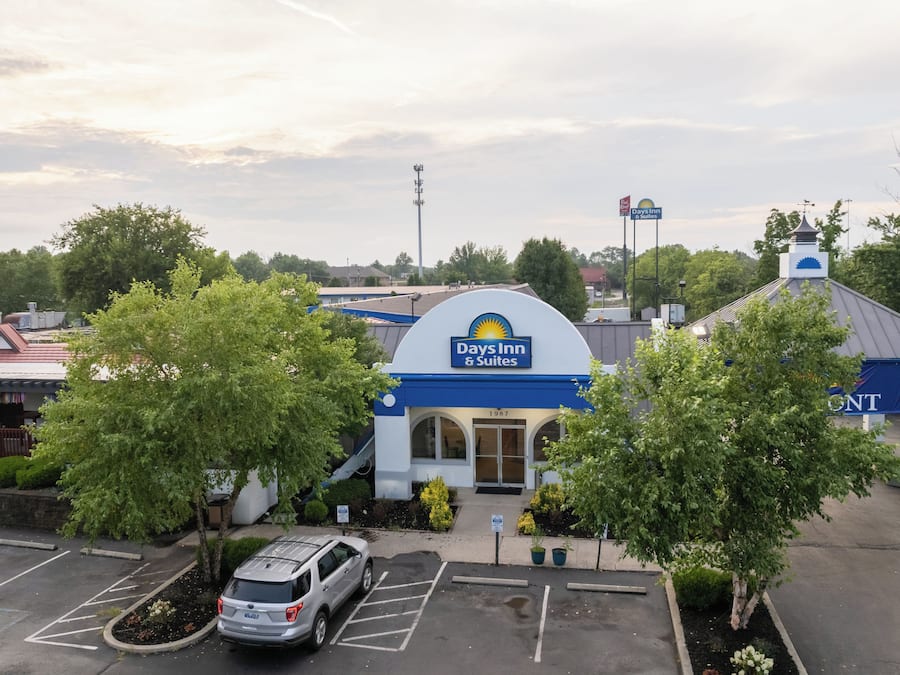 A Days Inn & Suites with a parking lot, a covered outdoor area, and a building with a blue and white color scheme.