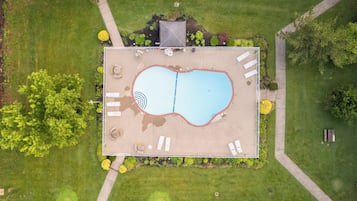 An aerial view of a rectangular swimming pool with a surrounding deck, lounge chairs, and a small garden area.