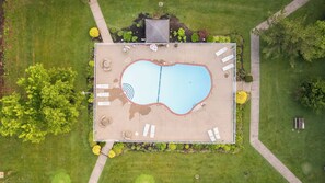 An aerial view of a rectangular swimming pool with a surrounding deck, lounge chairs, and a small garden area. - Days Inn & Suites by Wyndham Lexington (Lexington)