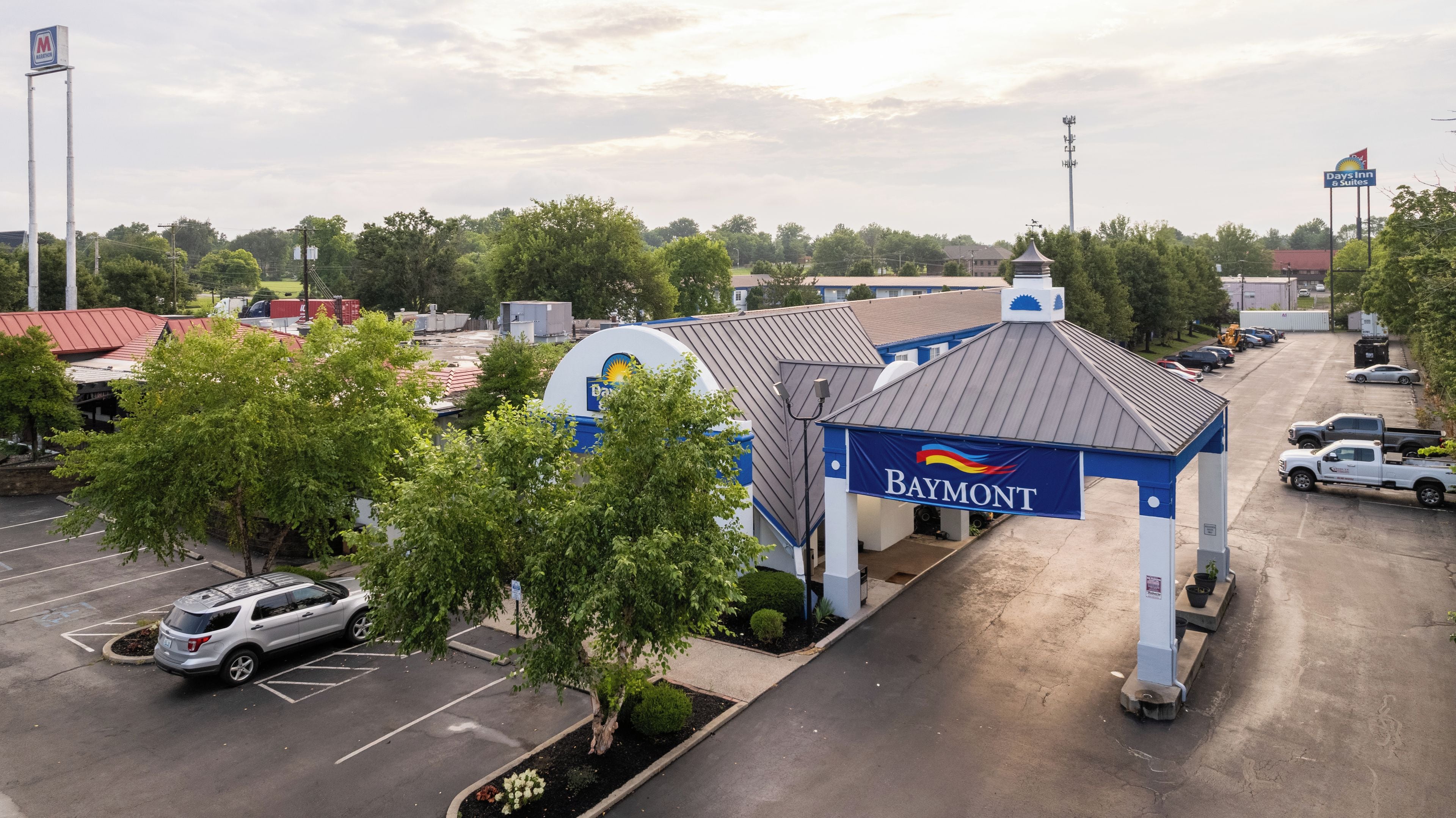 A Baymont hotel with a parking lot, a covered entrance, and a flag.