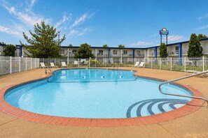 A swimming pool with a brick edge, surrounded by a white fence, and a Days Inn sign in the background. - Days Inn & Suites by Wyndham Lexington (Lexington)