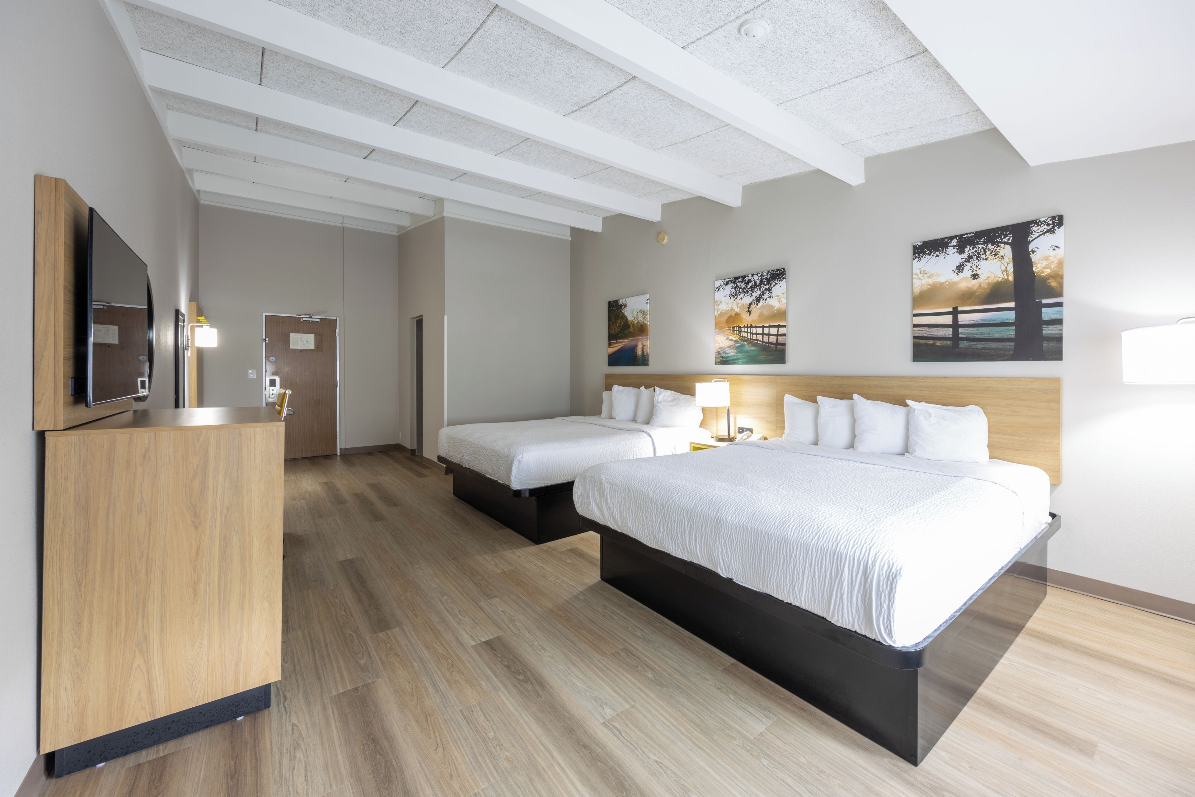 Una habitación de hotel con cama, mesitas de noche, escritorio y espejo.