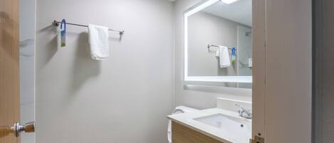 Un baño con inodoro, lavabo, espejo y toallero.