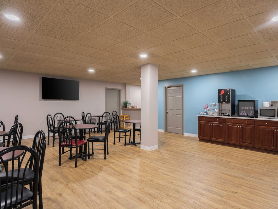 A dining area with tables and chairs, a kitchen area with appliances, and a flat-screen TV mounted on the wall.