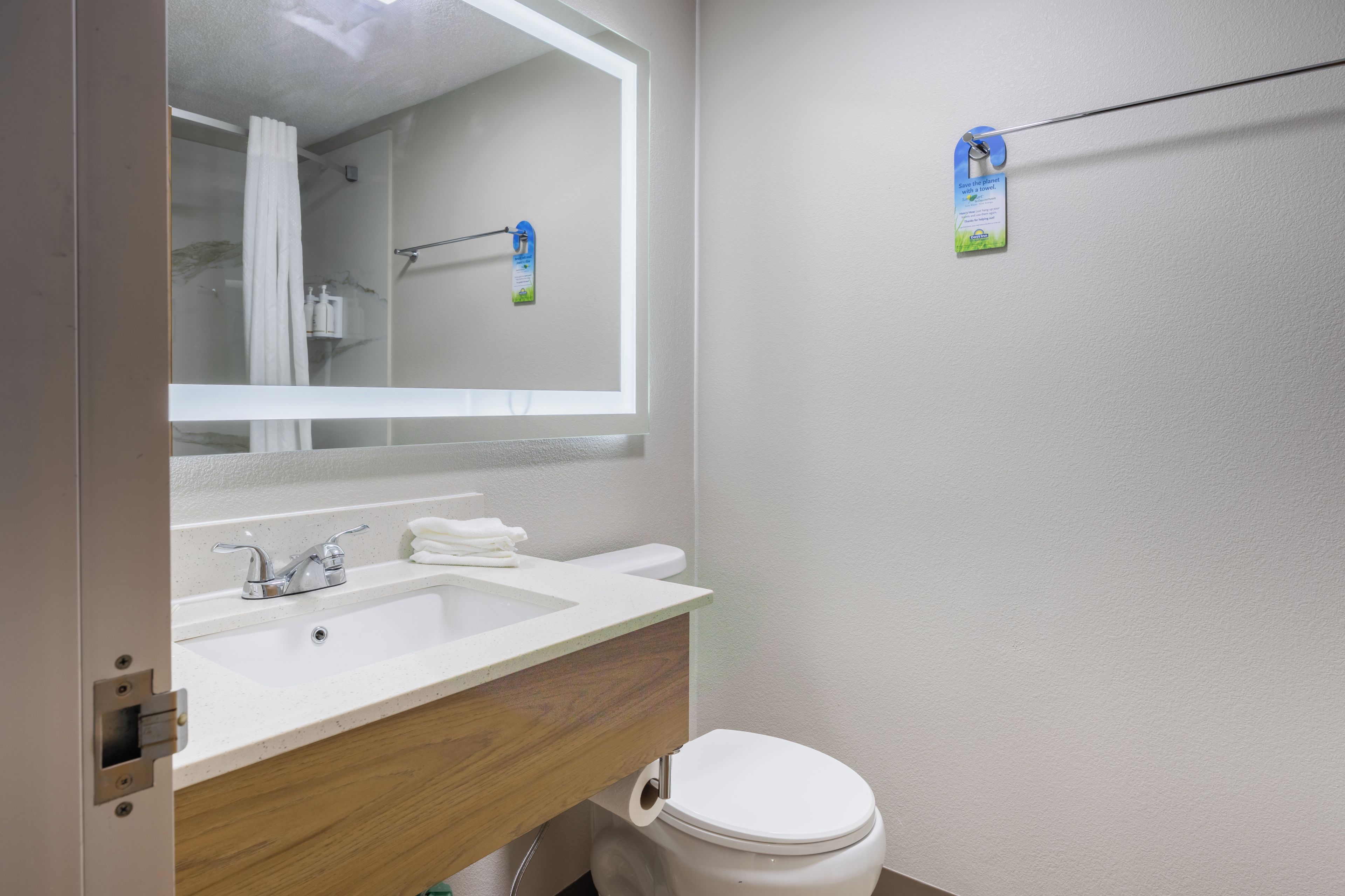 A bathroom with a white sink, mirror, and toilet.