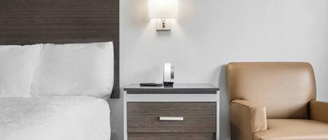 Een hotelkamer met een bed, een nachtkastje met een lamp en een leren fauteuil.