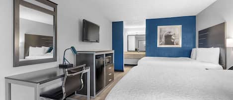 A hotel room with a bed, desk, chair, and a television.