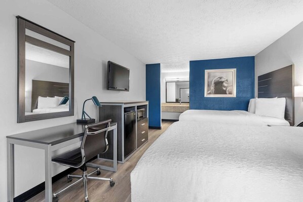 A hotel room with a bed, desk, chair, and a television.