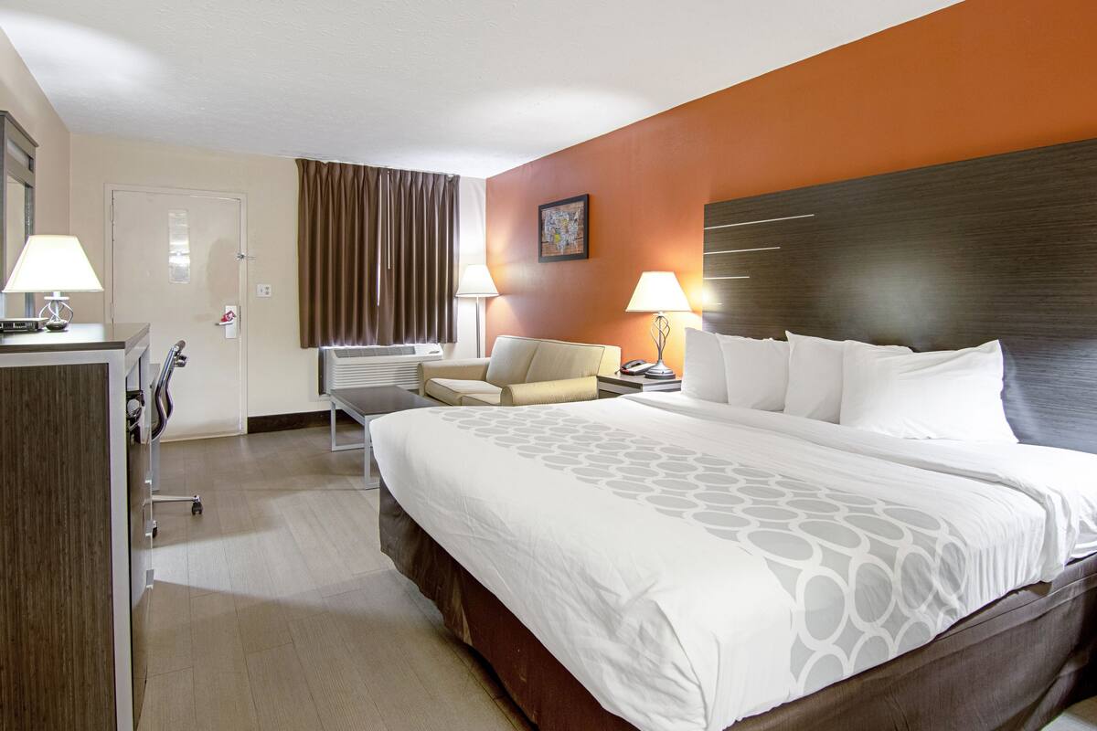 Ein Hotelzimmer mit einem großen Bett, einem Schreibtisch, einem Stuhl und einer Schreibtischlampe.