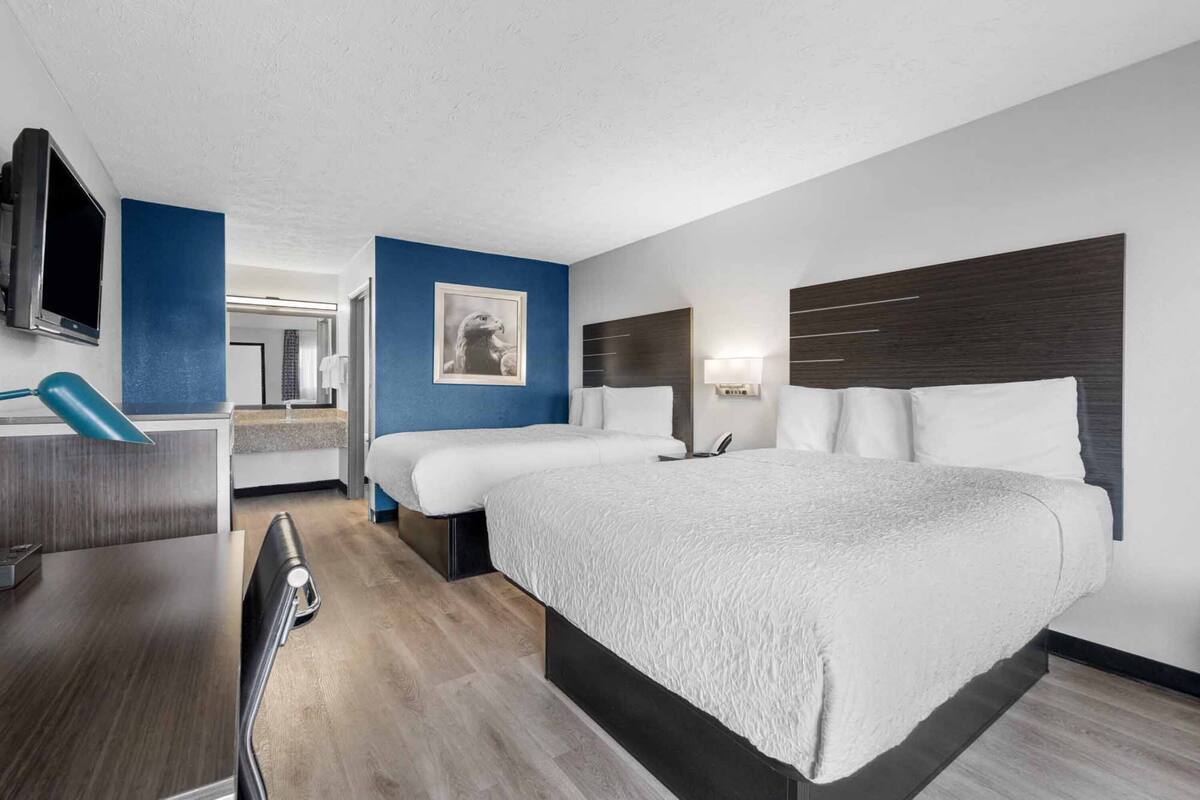 Ein modernes Hotelzimmer mit einem großen Bett, Nachttischen, einem Schreibtisch und einem Fernseher.