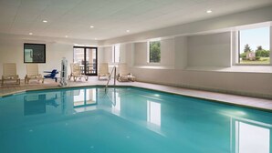 A large indoor swimming pool with clear blue water, surrounded by lounge chairs and a sunbed. - Baymont by Wyndham Georgetown/Lexington North (Georgetown)