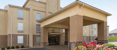 A hotel with a central entrance, a clock tower, and a covered walkway.