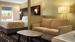 A hotel room with a bed, a sofa, a small table, and a bathtub. - Baymont by Wyndham Georgetown/Lexington North (Georgetown)
