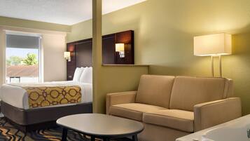 A hotel room with a bed, a sofa, a small table, and a bathroom.