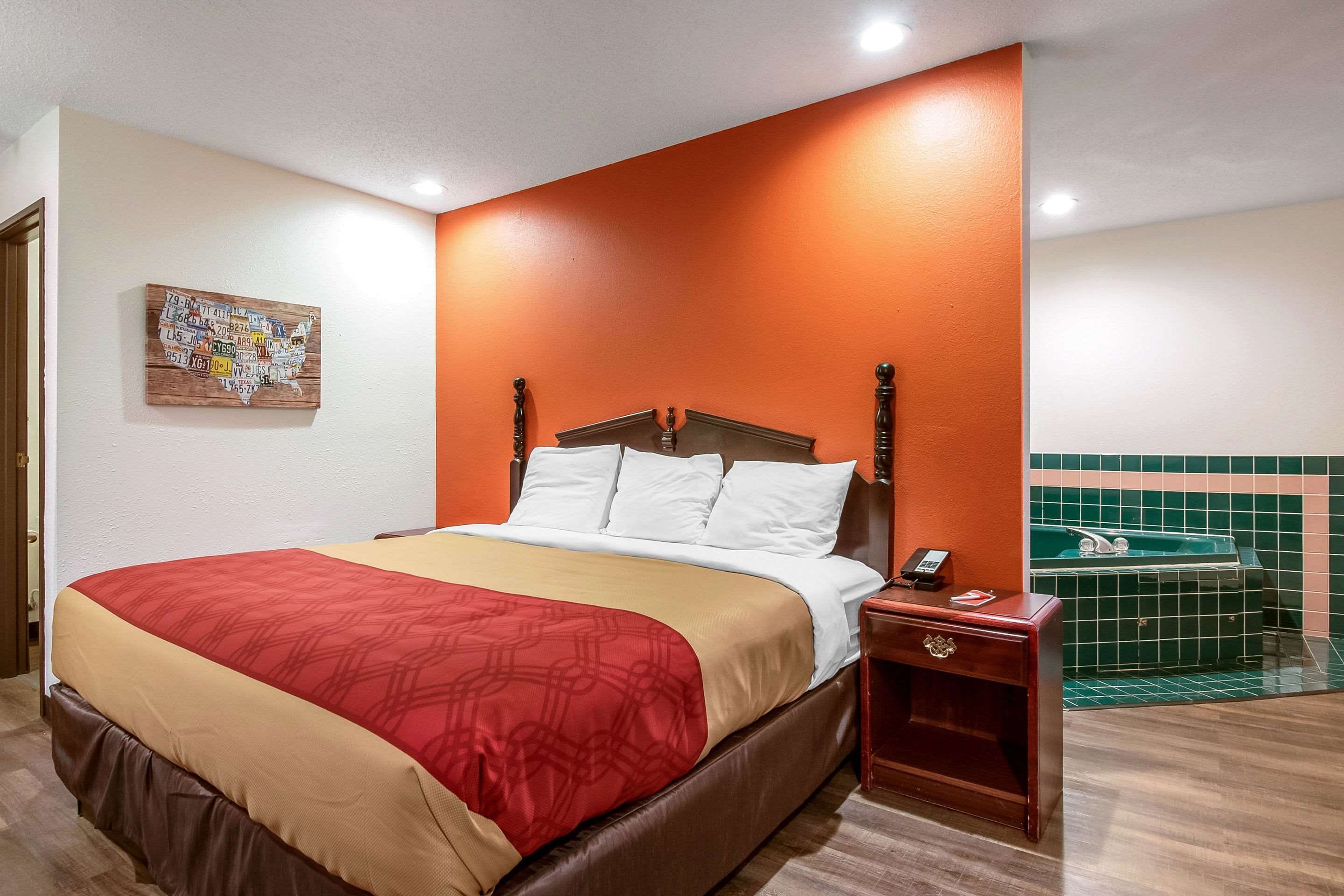 A hotel room with a bed, a nightstand, a telephone, and a wall-mounted artwork.