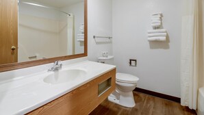 Un baño con tocador de madera, un lavabo blanco, un inodoro y un perchero para toallas.
