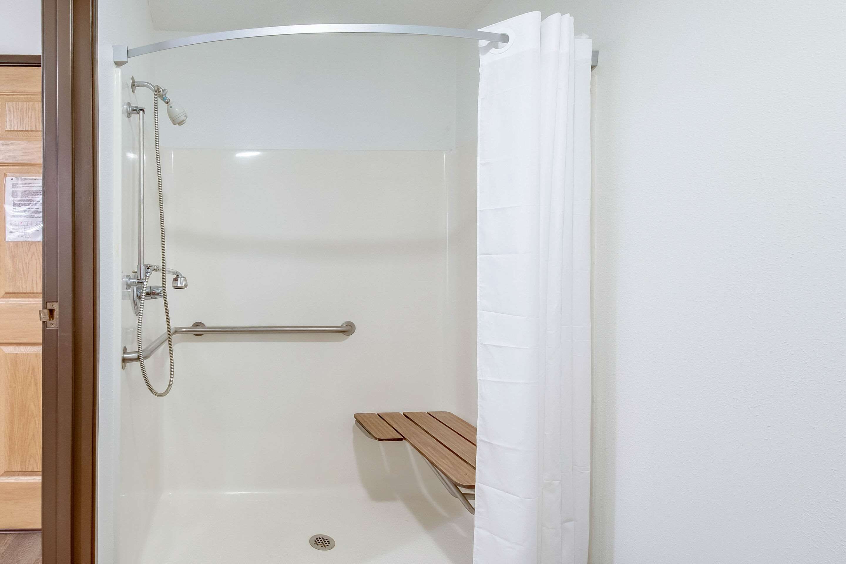 Une douche équipée d’un pommeau de douche à main, d’un flexible de douche et de commandes pour régler la douche.