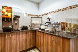 Une cuisine moderne équipée d’une machine à café, d’un présentoir à pain et d’une vitrine contenant des en-cas.