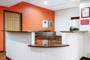 Un espace d’accueil doté d’une porte en bois, d’un comptoir surmonté d’un plateau en marbre et d’un thermostat fixé au mur.