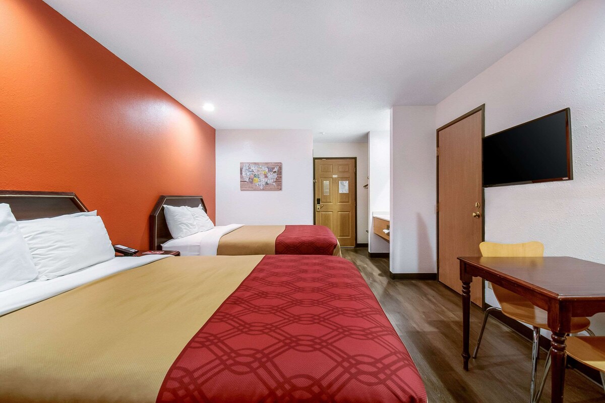 Une chambre d’hôtel avec deux lits, un bureau et une télévision.