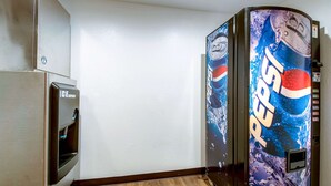 Habitación con refrigerador, máquina expendedora de Pepsi y piso de madera.