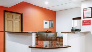 Un área de recepción con puerta de madera, mostrador con encimera de mármol y un termostato fijado a la pared.