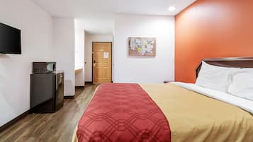 A hotel room with a bed, a television, a desk, and a door.