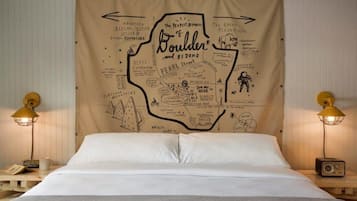 A bed with a map of Boulder and beyond, two lamps, and a radio on a bedside table.