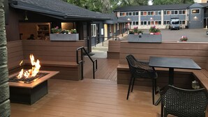 An outdoor patio area with a fire feature, seating, and planters with flowers. - Basecamp Boulder (Boulder)