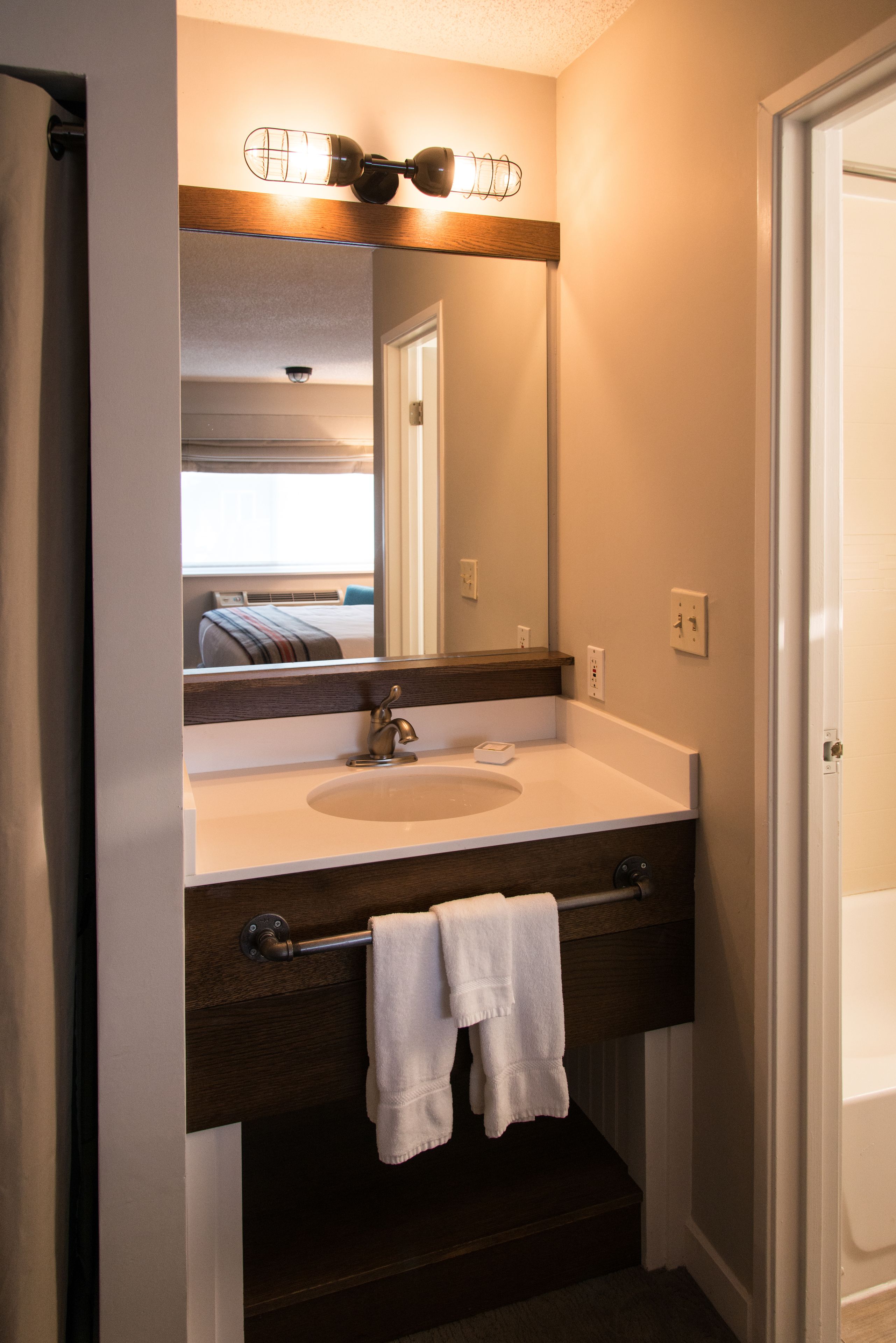 A bathroom with a white sink, a mirror, and a towel rack.