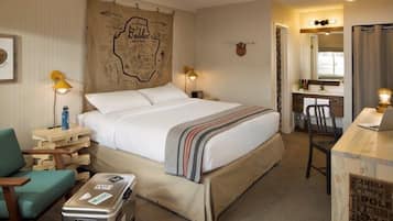 Een verzorgde hotelkamer met een bed, een bureau, een stoel en een koffer.