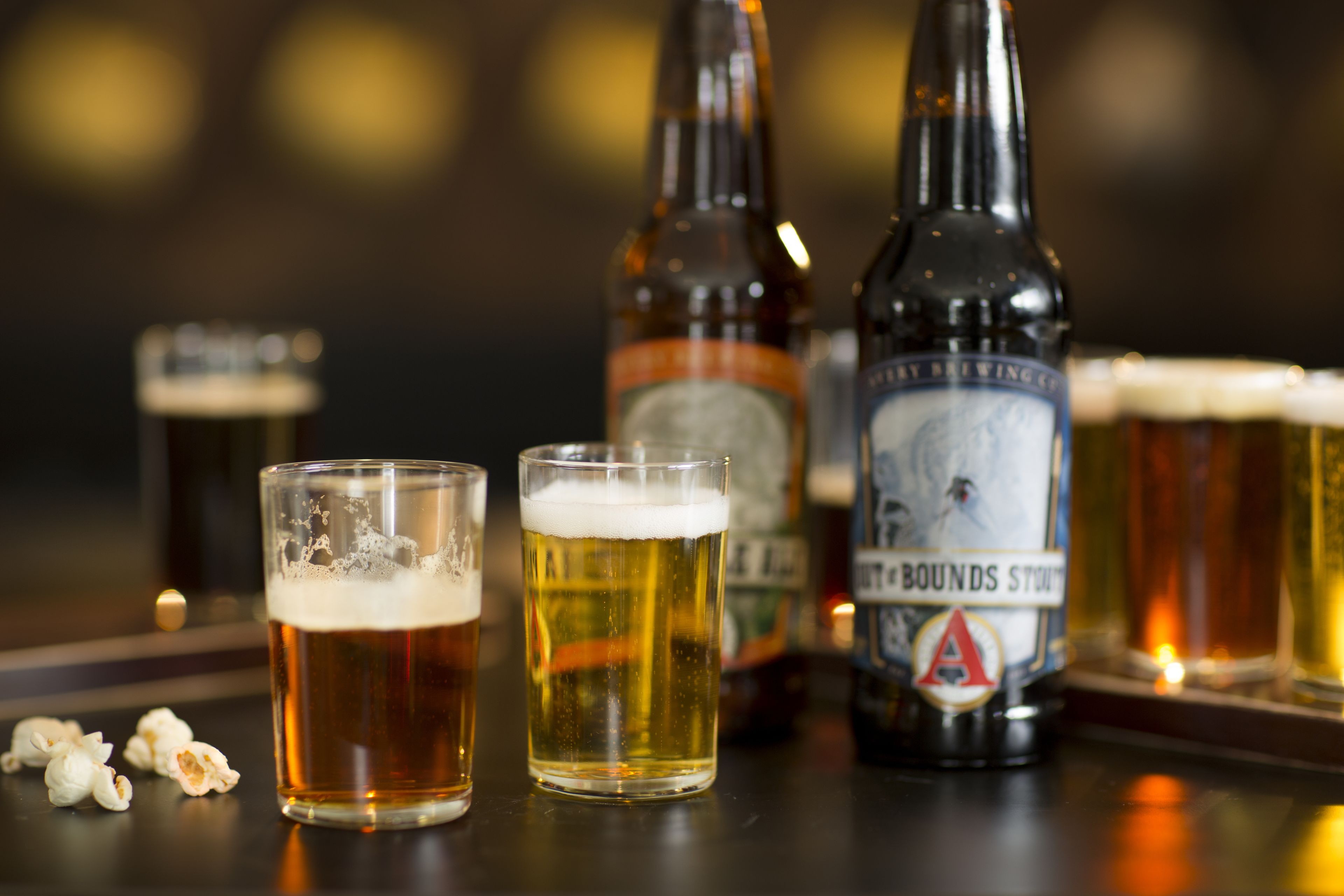 Eine Bar mit Biergläsern, einer Bierflasche und Popcorn auf einem Tisch.