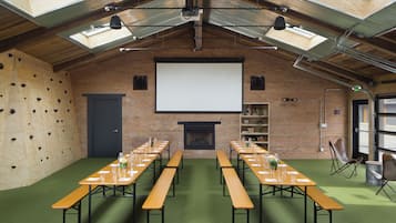 Ein Konferenzraum mit Projektionsleinwand, Tischen und Bänken.