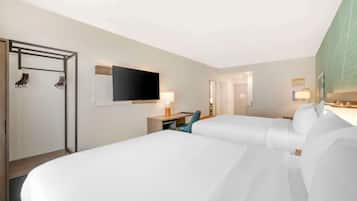 A hotel room with two beds, a desk with a chair, a TV, and a mirror.