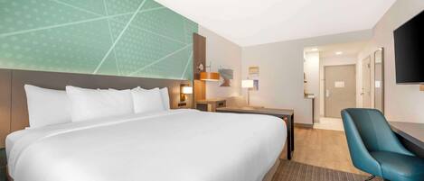 Habitación de hotel con una cama grande, un escritorio, una silla y un televisor.