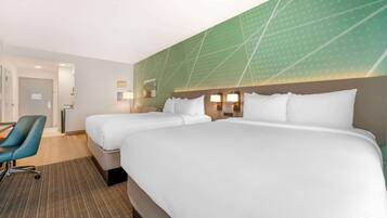 Een hotelkamer met twee bedden, een bureau en een stoel.