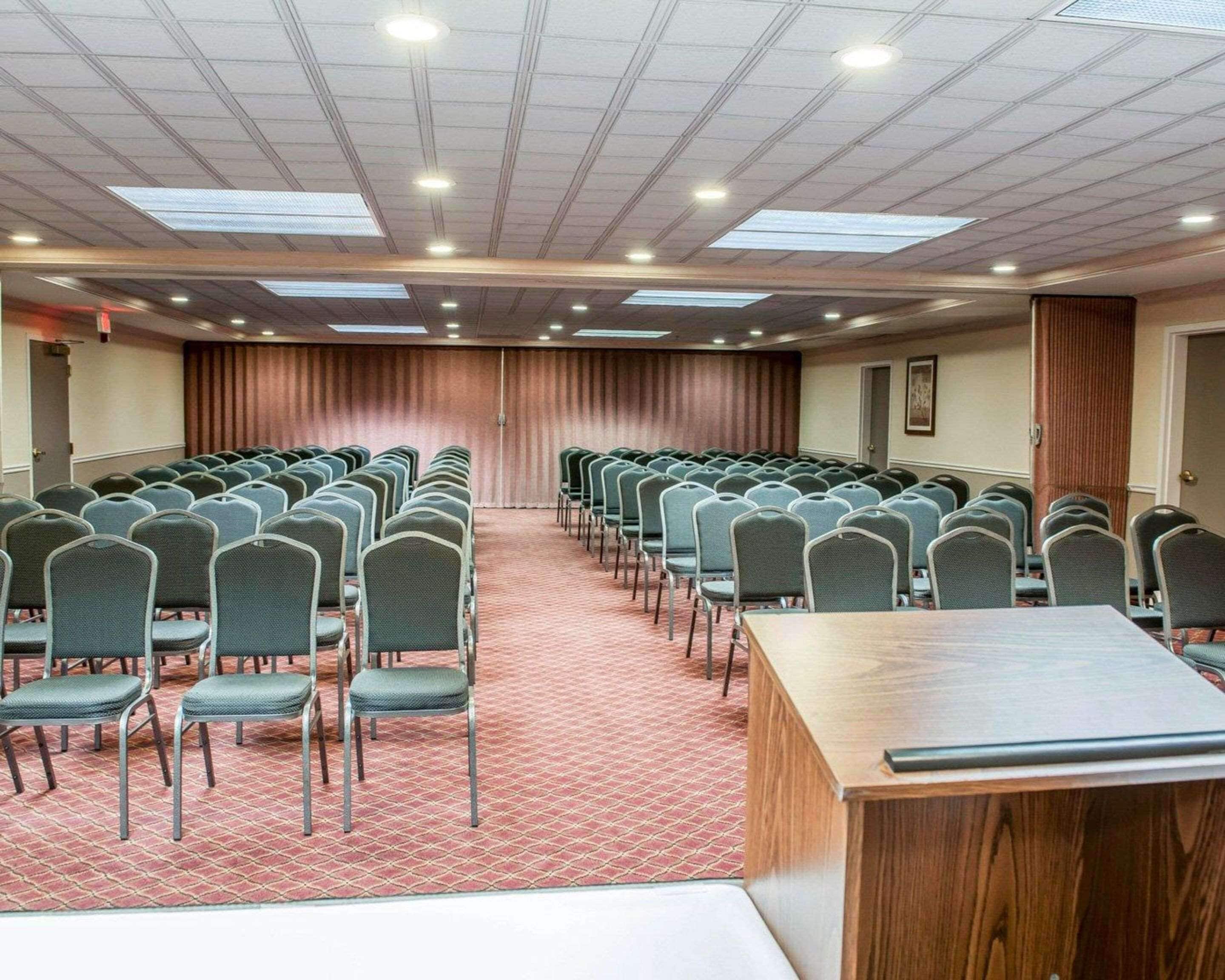 A conference room with rows of chairs, a long table, and a stage at the front.