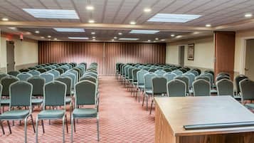A conference room with rows of chairs, a long table, and a stage at the front.