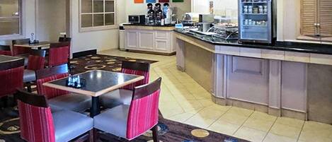 A hotel lobby with a dining area, a kitchen, and a bar.