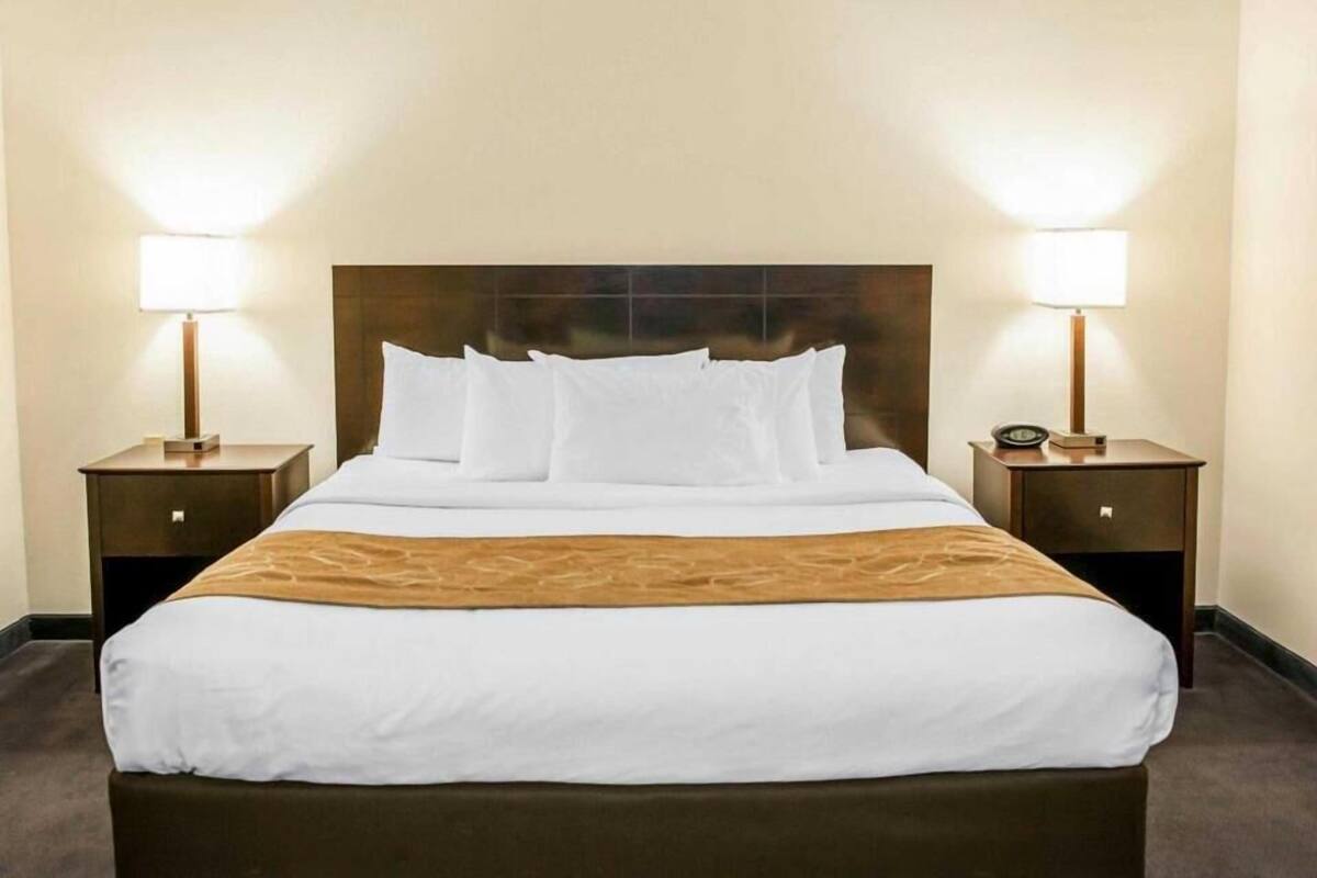 A hotel room with a large bed, two bedside tables with lamps, and a headboard.