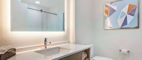 A bathroom with a large mirror, a sink, a toilet, and a towel rack.