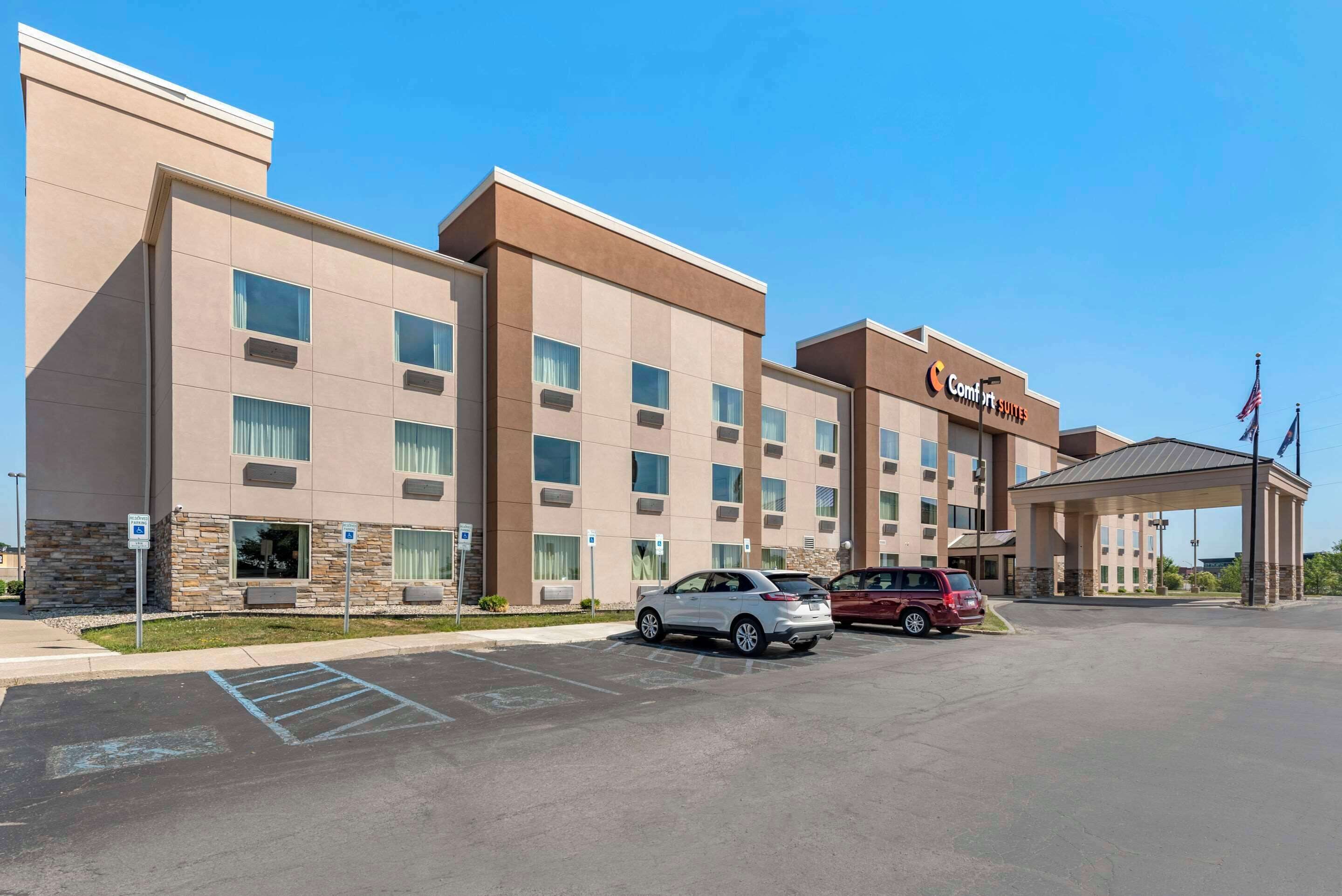 A hotel with a modern design, multiple floors, and a parking lot with several cars.