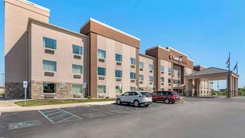 A hotel with a modern design, multiple floors, and a parking lot with several cars.