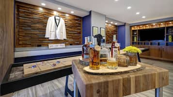 Zona de bar amb decoració de fusta, taula de bitlles i diverses ampolles de licors.