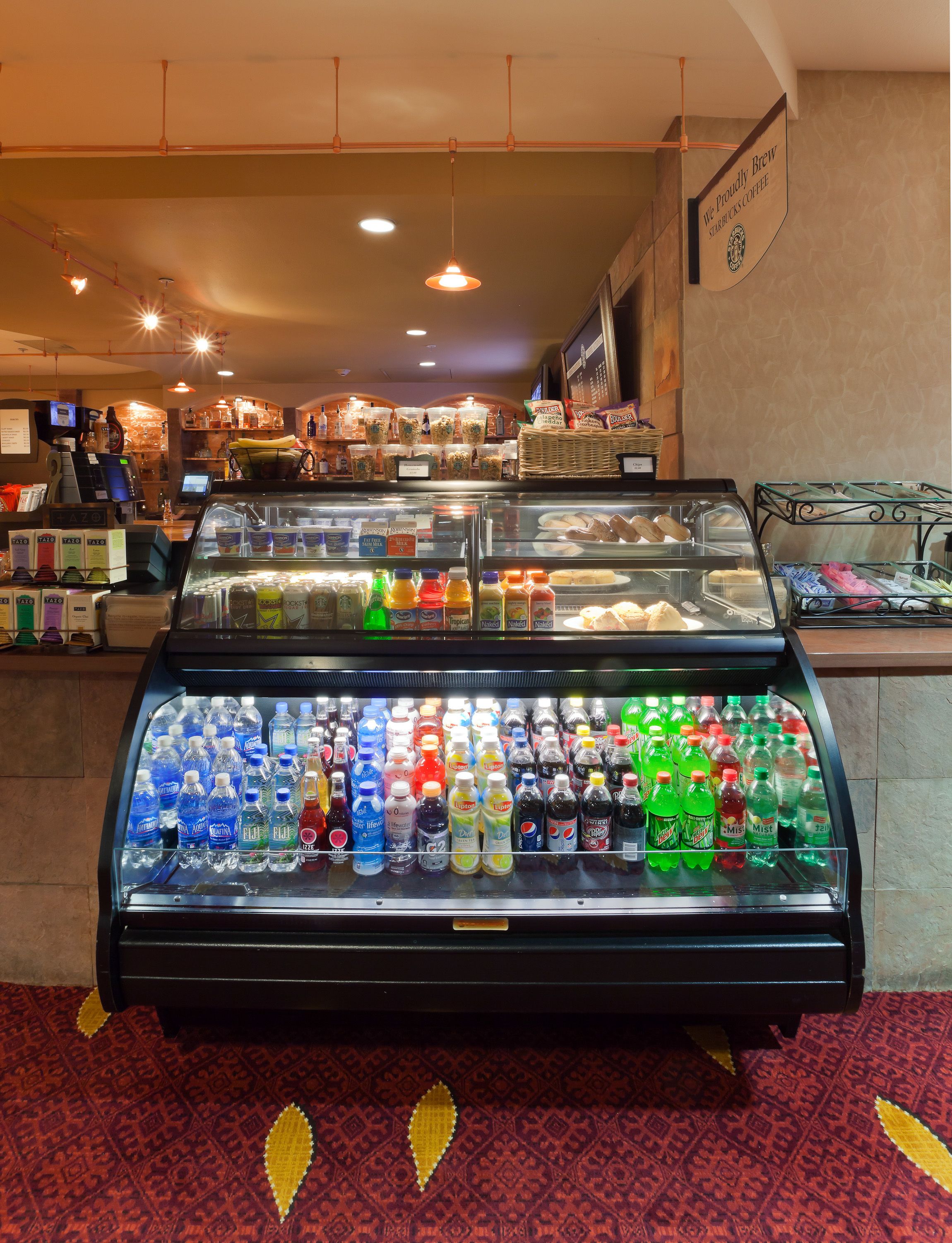 A beverage display case in a coffee shop with various drinks and a sign above it.
