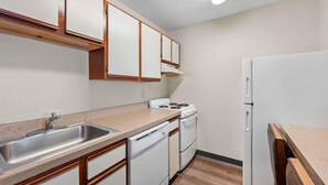 A compact kitchen with a sink, stove, and dishwasher. - Extended Stay America Suites Fort Wayne North (Fort Wayne)