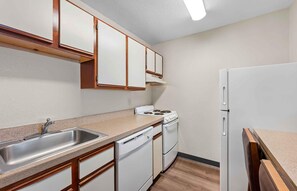 A compact kitchen with a sink, stove, and dishwasher. - Extended Stay America Suites Fort Wayne North (Fort Wayne)
