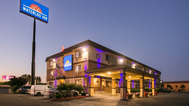 Un hotel con un cartel que dice "Waterloo Inn", que presenta una estructura de dos pisos con un vestíbulo cubierto y un estacionamiento al frente.