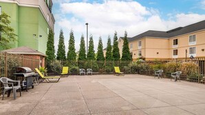 Une cour avec un espace barbecue, des sièges extérieurs et une clôture.